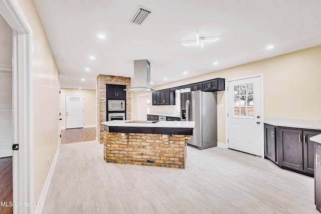 kitchen featuring island exhaust hood, appliances with stainless steel finishes, a center island, and light wood-type flooring