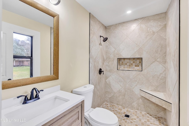 bathroom with tiled shower, vanity, and toilet