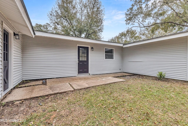 doorway to property with a patio area and a yard