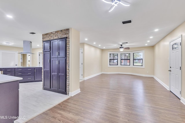 kitchen with stovetop, island range hood, light hardwood / wood-style flooring, and ceiling fan