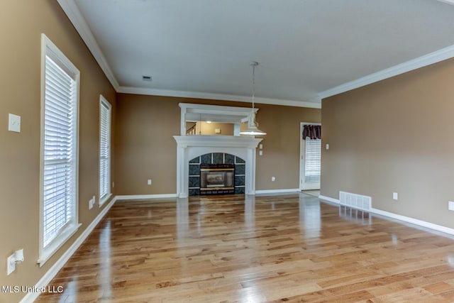 unfurnished living room with light hardwood / wood-style flooring, ornamental molding, and a tiled fireplace