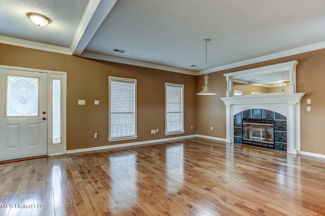 unfurnished living room featuring hardwood / wood-style flooring, ornamental molding, a textured ceiling, and a tile fireplace