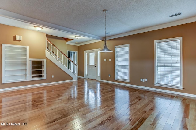 unfurnished living room featuring crown molding, light hardwood / wood-style floors, and a textured ceiling