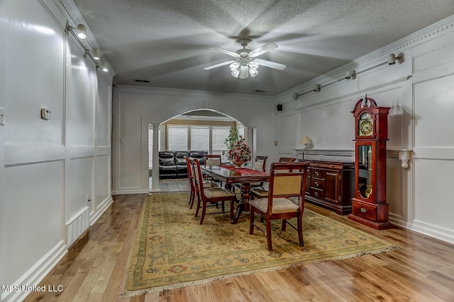 dining room with a textured ceiling, ceiling fan, crown molding, and light hardwood / wood-style flooring