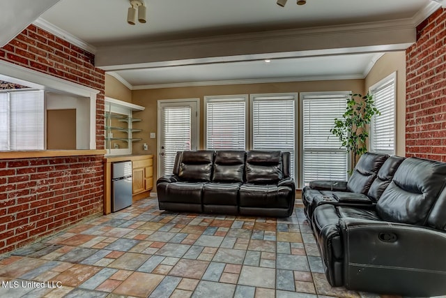 living room featuring a healthy amount of sunlight, crown molding, and brick wall