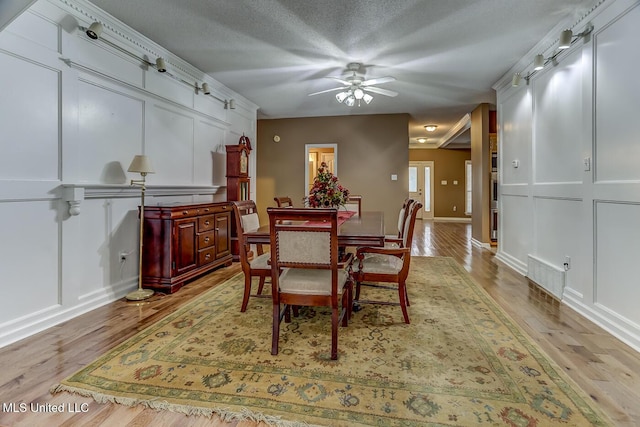 dining area featuring ceiling fan, light wood-type flooring, and a textured ceiling