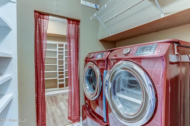 clothes washing area with washer and clothes dryer and light wood-type flooring