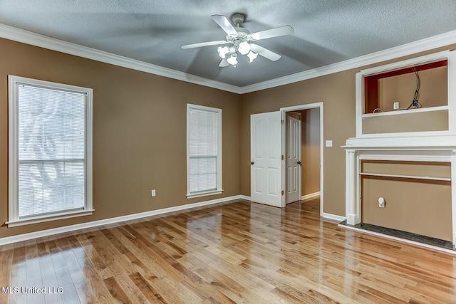 unfurnished living room with ceiling fan, a healthy amount of sunlight, hardwood / wood-style floors, a textured ceiling, and ornamental molding