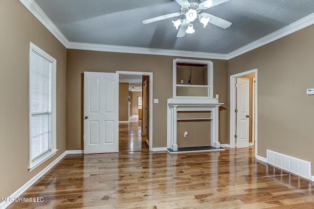 empty room featuring hardwood / wood-style flooring, ceiling fan, crown molding, and a textured ceiling