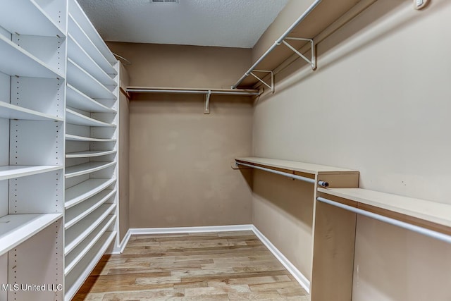 walk in closet with light hardwood / wood-style floors