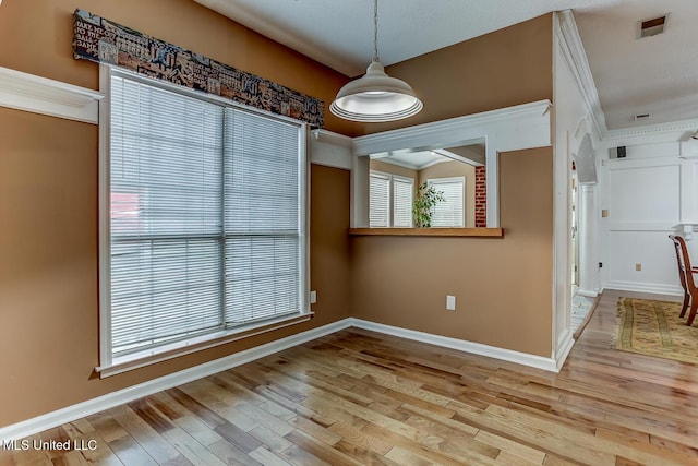 unfurnished dining area featuring a healthy amount of sunlight, crown molding, and light hardwood / wood-style flooring