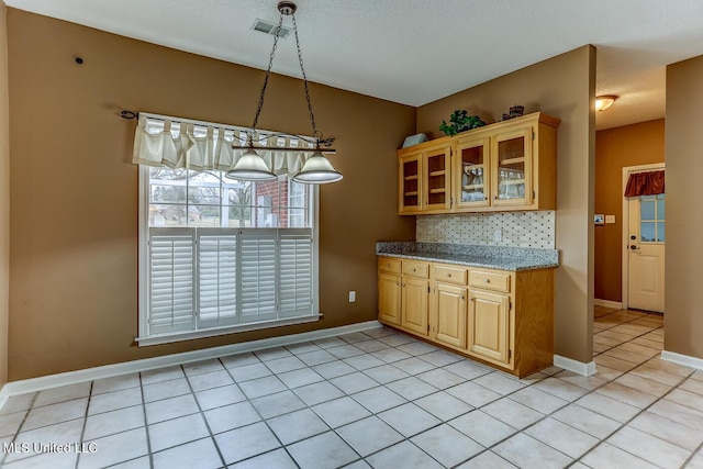 kitchen featuring decorative backsplash, light tile patterned floors, light stone counters, and decorative light fixtures