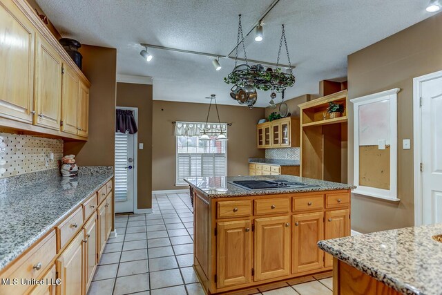 kitchen with decorative backsplash, a textured ceiling, light tile patterned floors, a center island, and stainless steel gas stovetop