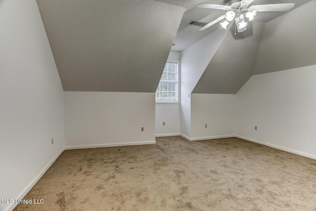 additional living space featuring carpet flooring, lofted ceiling, ceiling fan, and a textured ceiling