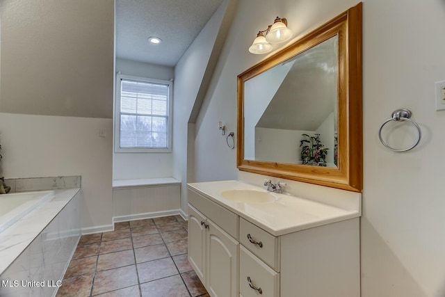 bathroom featuring vanity, a textured ceiling, vaulted ceiling, and tile patterned flooring