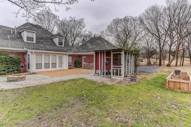 exterior space with a patio area, a sunroom, a yard, and a fire pit