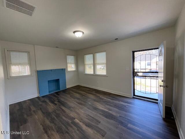 unfurnished living room featuring a wealth of natural light and dark wood-type flooring