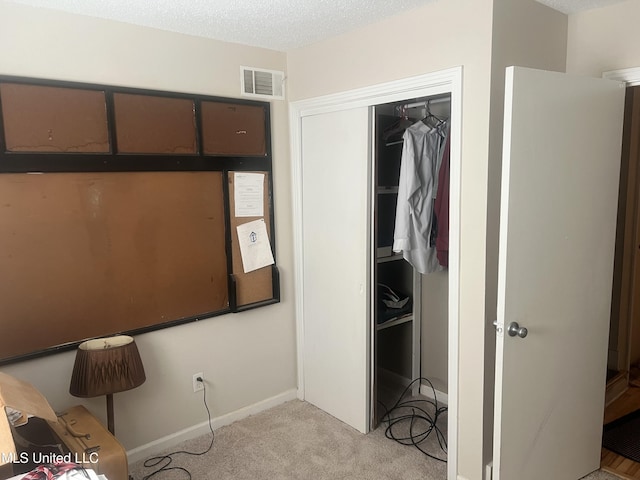 unfurnished bedroom with a closet, a textured ceiling, and light carpet