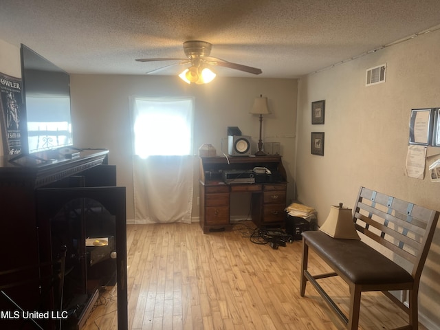 office area featuring ceiling fan, light hardwood / wood-style floors, and a textured ceiling