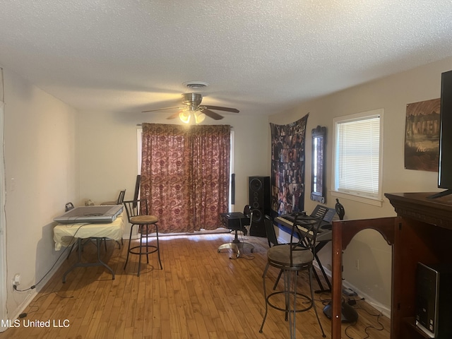 dining space with light wood-type flooring, a textured ceiling, and ceiling fan