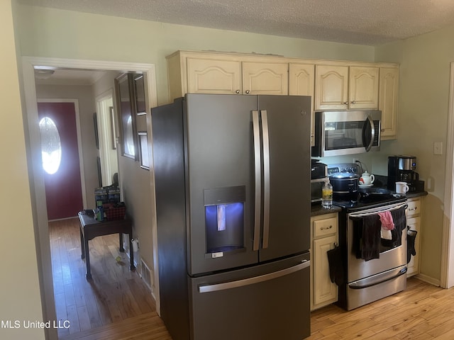 kitchen with light wood-type flooring, a textured ceiling, and appliances with stainless steel finishes