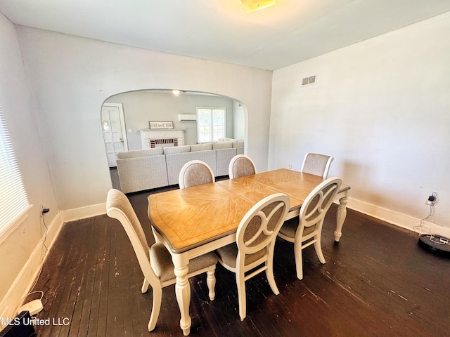 340 Elm Ave, Clarksdale, MS 38614 - dining space featuring hardwood / wood-style flooring, arched walkways, a wall mounted AC, and baseboards