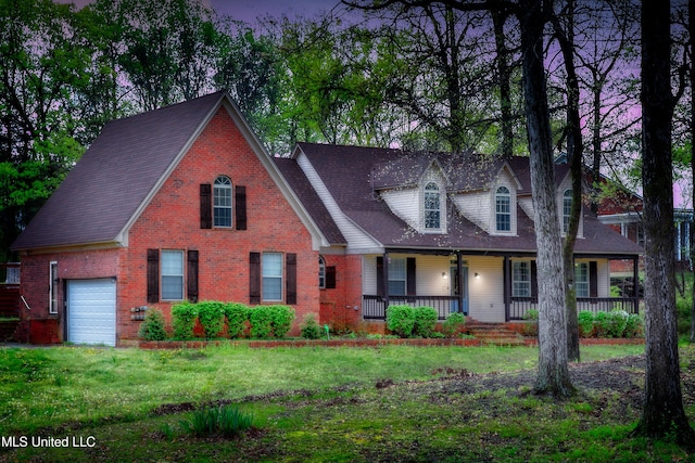 view of front of home featuring brick siding, covered porch, a front lawn, and a garage