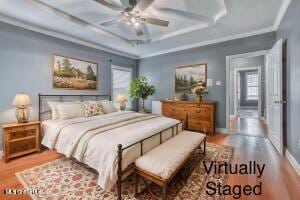 bedroom featuring wood finished floors, multiple windows, ornamental molding, and baseboards