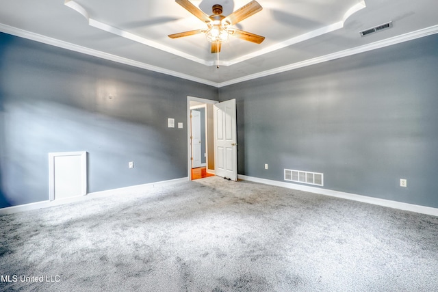 carpeted spare room featuring a raised ceiling, ceiling fan, crown molding, and baseboards