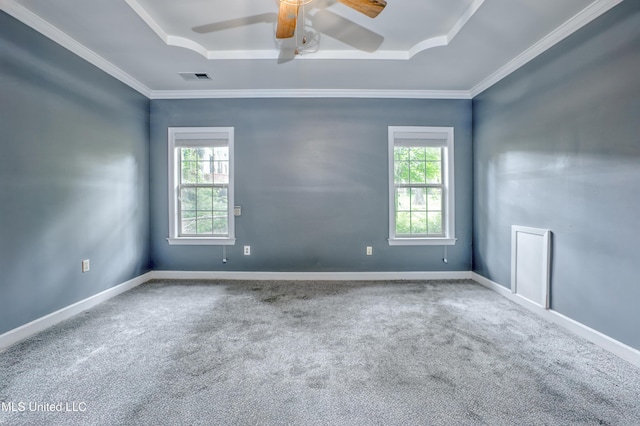 empty room with carpet floors, a ceiling fan, crown molding, a tray ceiling, and baseboards