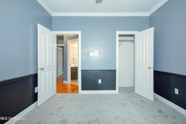 unfurnished bedroom with crown molding, carpet flooring, a closet, and baseboards