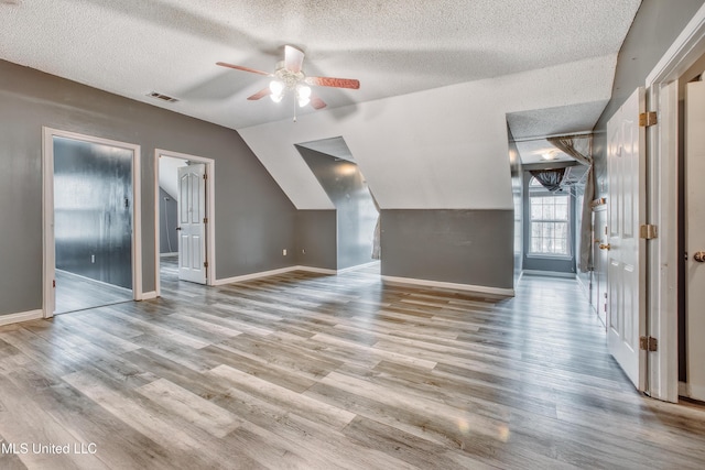 additional living space featuring a textured ceiling, ceiling fan, lofted ceiling, wood finished floors, and baseboards