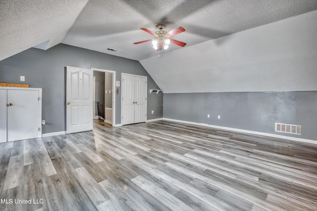 bonus room with vaulted ceiling, ceiling fan, a textured ceiling, baseboards, and wood finished floors