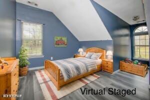 bedroom with multiple windows, wood finished floors, baseboards, and vaulted ceiling
