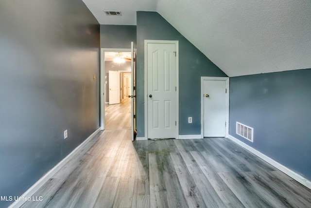 bonus room featuring vaulted ceiling, wood finished floors, a textured ceiling, and baseboards
