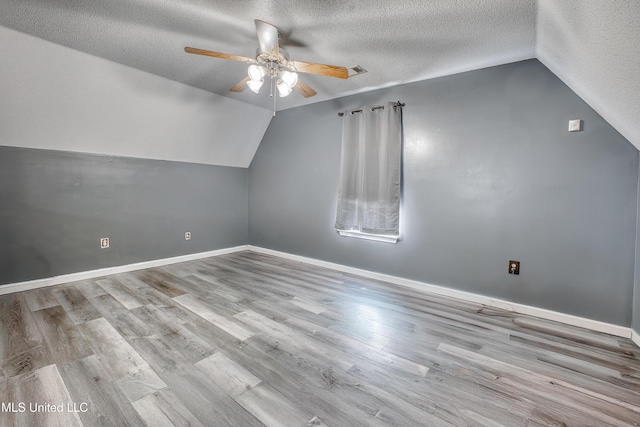 bonus room featuring lofted ceiling, a ceiling fan, a textured ceiling, wood finished floors, and baseboards
