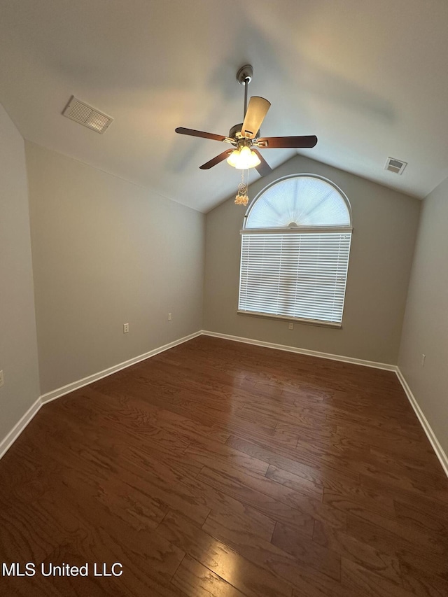 empty room with lofted ceiling, ceiling fan, dark wood-style flooring, and visible vents