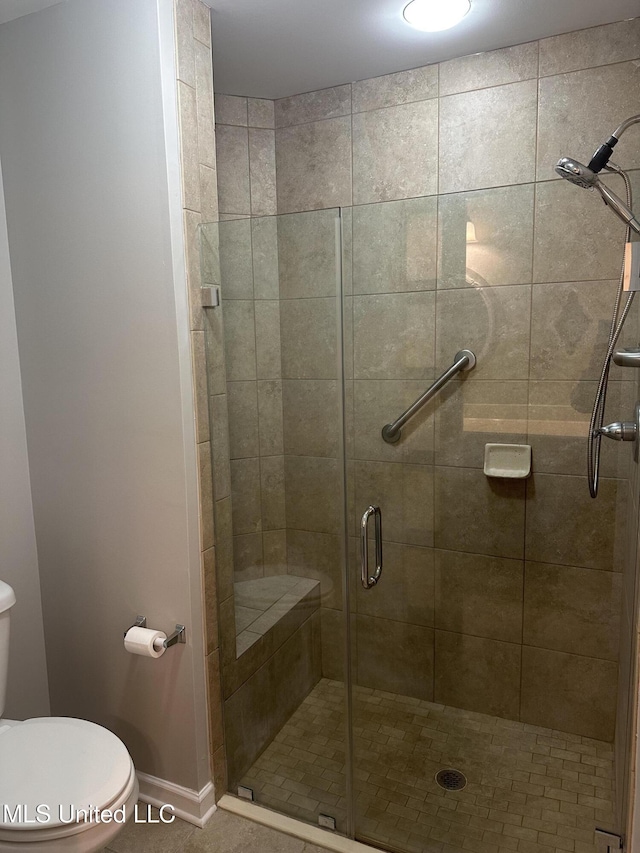 full bathroom with a shower stall, toilet, and baseboards