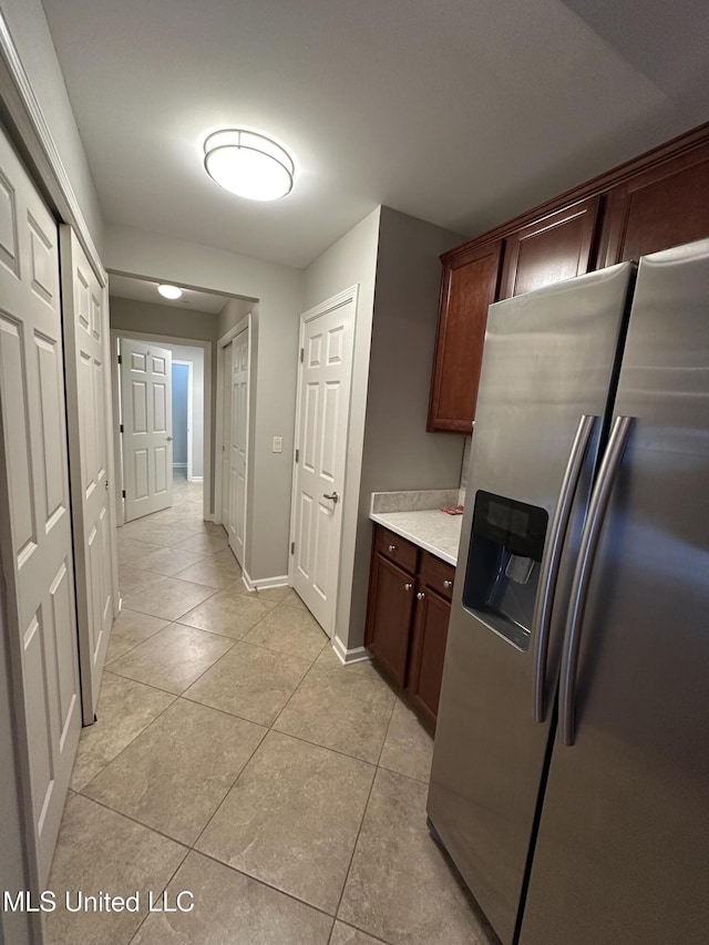 kitchen with light countertops, stainless steel fridge, baseboards, and light tile patterned floors