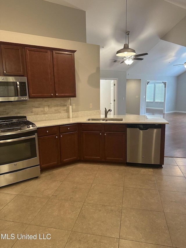 kitchen featuring light countertops, decorative backsplash, appliances with stainless steel finishes, a ceiling fan, and a sink