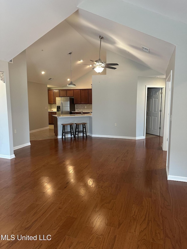 unfurnished living room featuring baseboards, ceiling fan, visible vents, and dark wood-type flooring