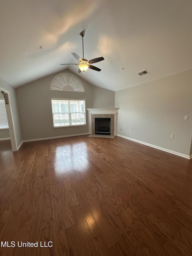 unfurnished living room with dark wood-style floors, visible vents, a tiled fireplace, a ceiling fan, and vaulted ceiling