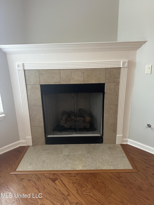 room details featuring baseboards, wood finished floors, and a tile fireplace