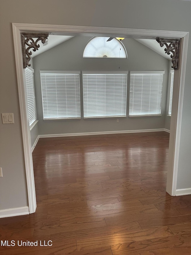 empty room with baseboards, vaulted ceiling, and wood finished floors