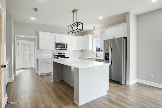 kitchen featuring a center island, visible vents, decorative backsplash, appliances with stainless steel finishes, and a sink