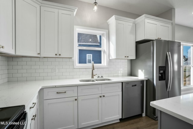 kitchen with appliances with stainless steel finishes, white cabinets, a sink, and decorative backsplash