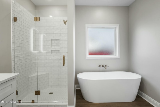 bathroom featuring a freestanding bath, a stall shower, and wood finished floors