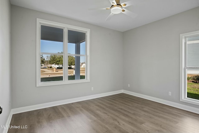 empty room featuring a wealth of natural light, baseboards, and wood finished floors