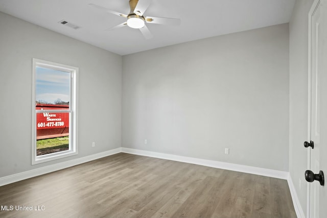 spare room featuring baseboards, visible vents, and wood finished floors