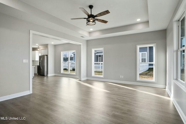 unfurnished room with dark wood-style floors, a tray ceiling, recessed lighting, and baseboards